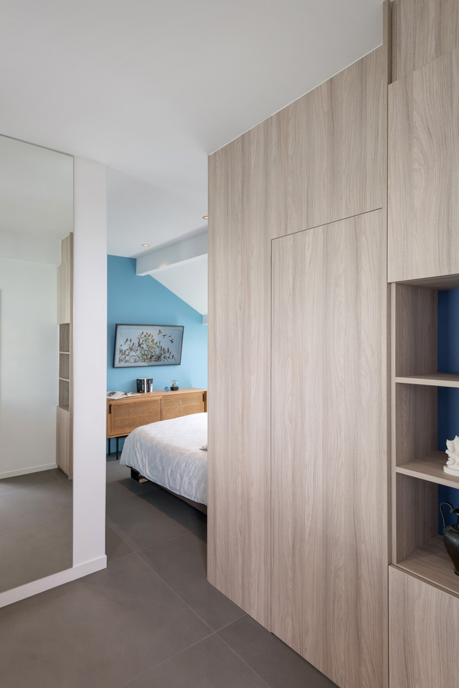 Photo of a mid-sized contemporary gender-neutral walk-in wardrobe in Lyon with beaded inset cabinets, light wood cabinets, concrete floors and grey floor.