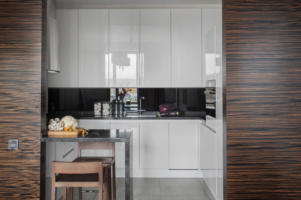 Design ideas for a small contemporary u-shaped open plan kitchen in Moscow with an undermount sink, flat-panel cabinets, white cabinets, black splashback and a peninsula.