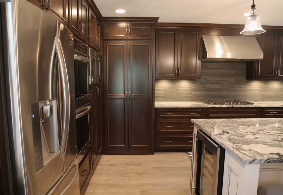 Example of a mid-sized transitional l-shaped porcelain tile eat-in kitchen design with an undermount sink, raised-panel cabinets, dark wood cabinets, granite countertops, gray backsplash, porcelain backsplash, stainless steel appliances and an island