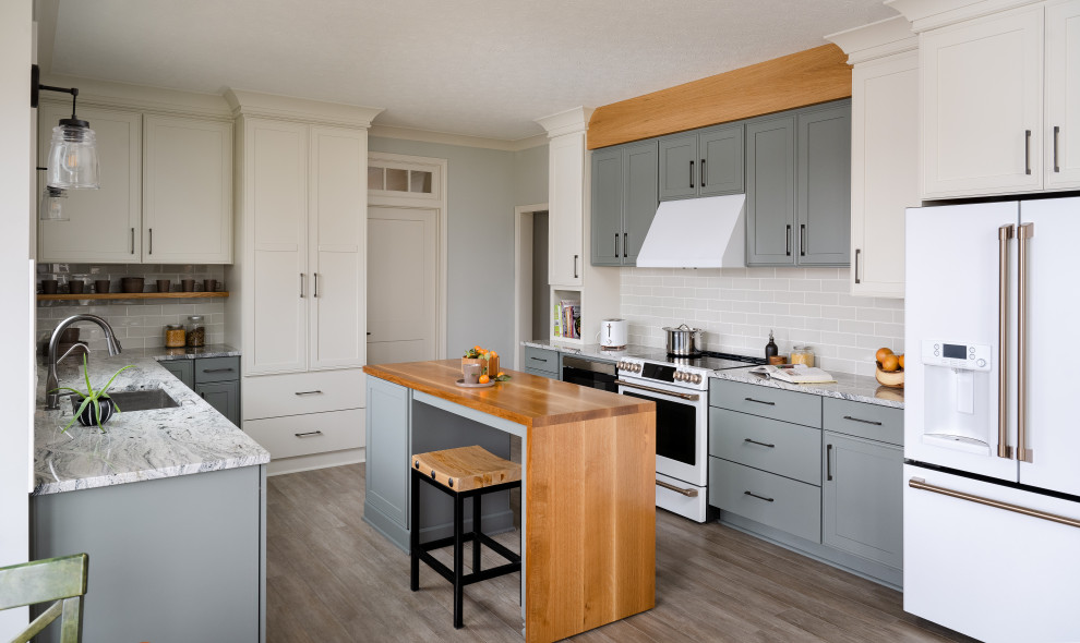 Mid-sized minimalist u-shaped light wood floor eat-in kitchen photo in Indianapolis with an undermount sink, shaker cabinets, white cabinets, granite countertops, beige backsplash, stainless steel appliances and an island