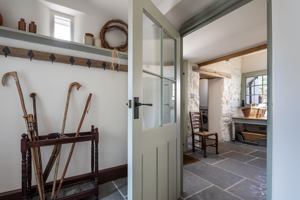 Photo of a large traditional galley dedicated laundry room in Other with a farmhouse sink, shaker cabinets, green cabinets, granite benchtops, white walls, slate floors, a concealed washer and dryer, blue floor and grey benchtop.
