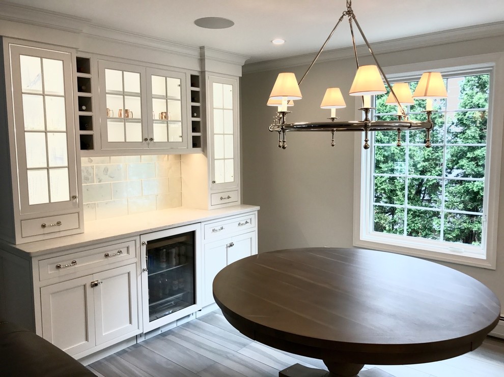 Open concept kitchen - mid-sized transitional u-shaped light wood floor and brown floor open concept kitchen idea with a farmhouse sink, recessed-panel cabinets, white cabinets, marble countertops, white backsplash, marble backsplash, stainless steel appliances and an island