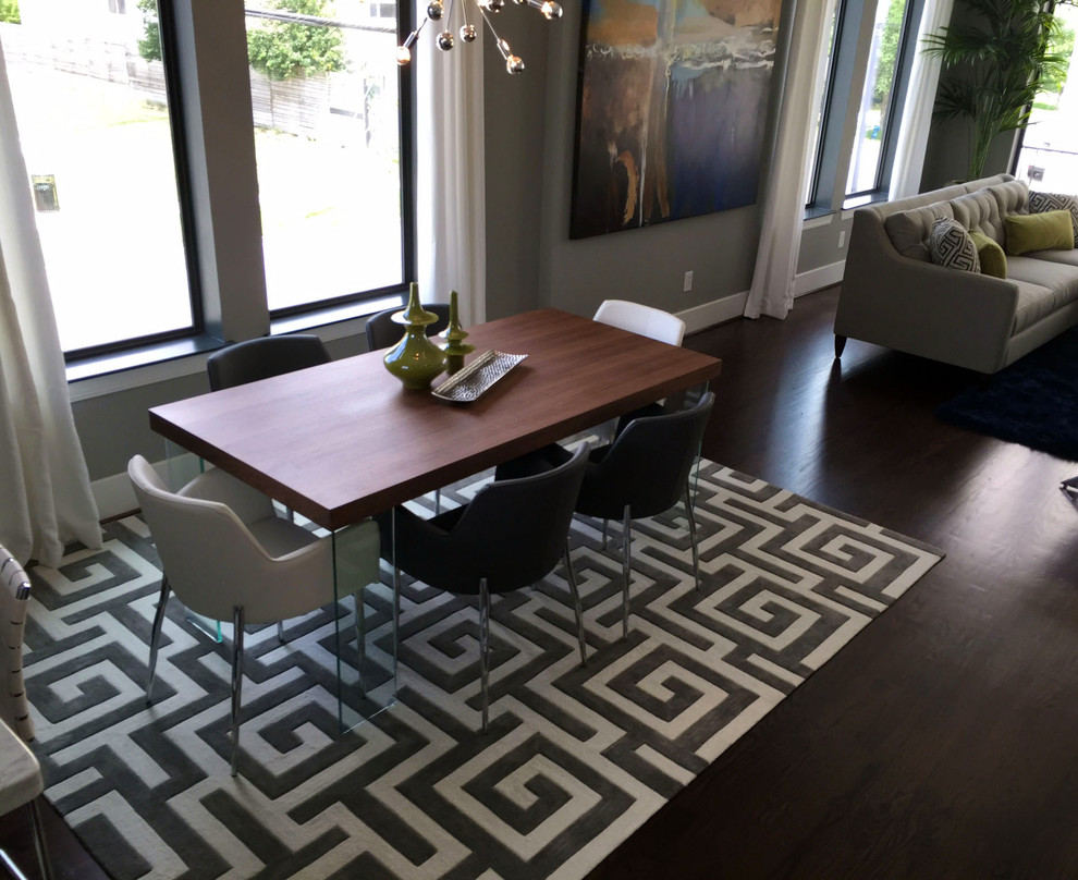 This is an example of a small modern dining room in Houston with grey walls, dark hardwood floors, a standard fireplace, a metal fireplace surround and brown floor.