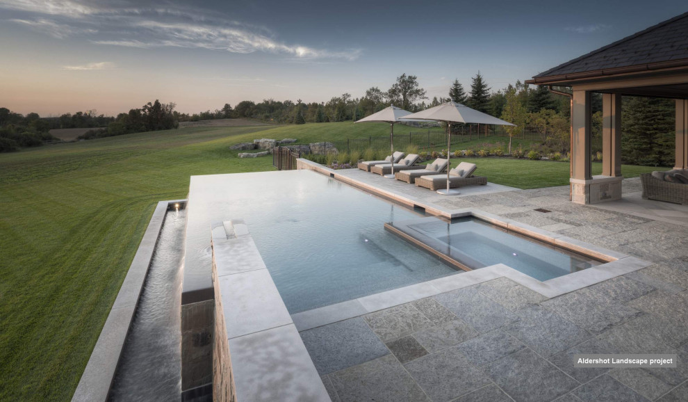 Inspiration for a mid-sized transitional backyard stone and rectangular infinity pool landscaping remodel in Toronto