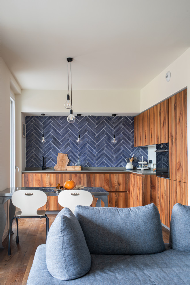 Modern inredning av ett mellanstort grå grått kök, med en undermonterad diskho, släta luckor, marmorbänkskiva, blått stänkskydd, stänkskydd i stickkakel, svarta vitvaror, mörkt trägolv och brunt golv