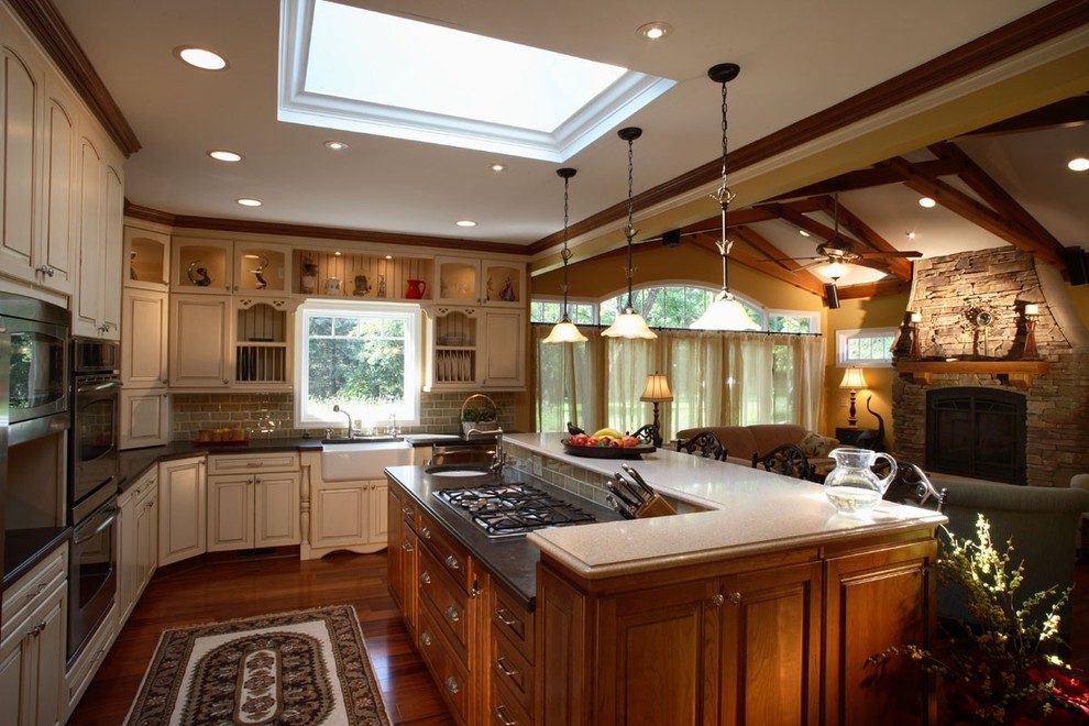 Open concept kitchen - rustic l-shaped medium tone wood floor open concept kitchen idea in DC Metro with a farmhouse sink, raised-panel cabinets, beige cabinets, gray backsplash, stainless steel appliances and an island