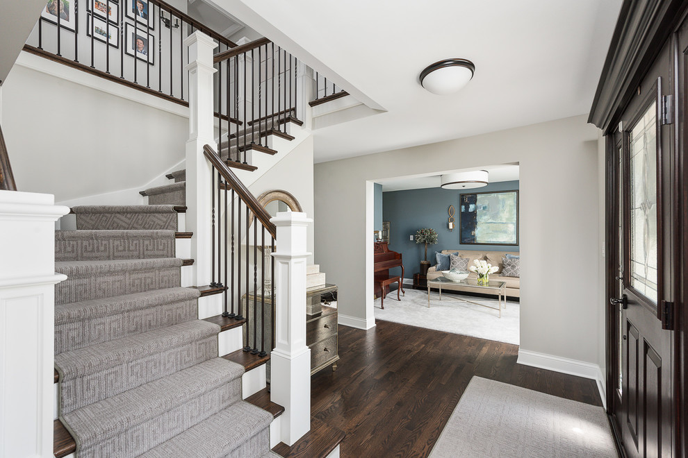 This is an example of a large transitional foyer in Chicago with grey walls, dark hardwood floors, a pivot front door, a dark wood front door and brown floor.