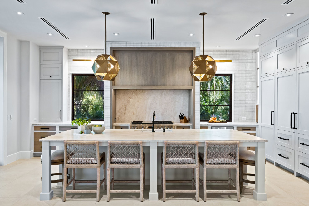 Inspiration for a mid-sized contemporary galley ceramic tile and beige floor eat-in kitchen remodel in Grand Rapids with an undermount sink, recessed-panel cabinets, white cabinets, limestone countertops, beige backsplash, limestone backsplash, black appliances, an island and beige countertops