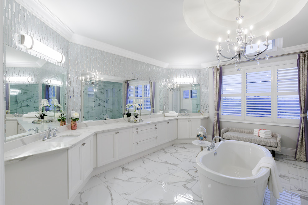 Inspiration for a transitional bathroom in Toronto with recessed-panel cabinets, white cabinets, a freestanding tub, gray tile, mosaic tile, grey walls, an undermount sink, white floor and white benchtops.