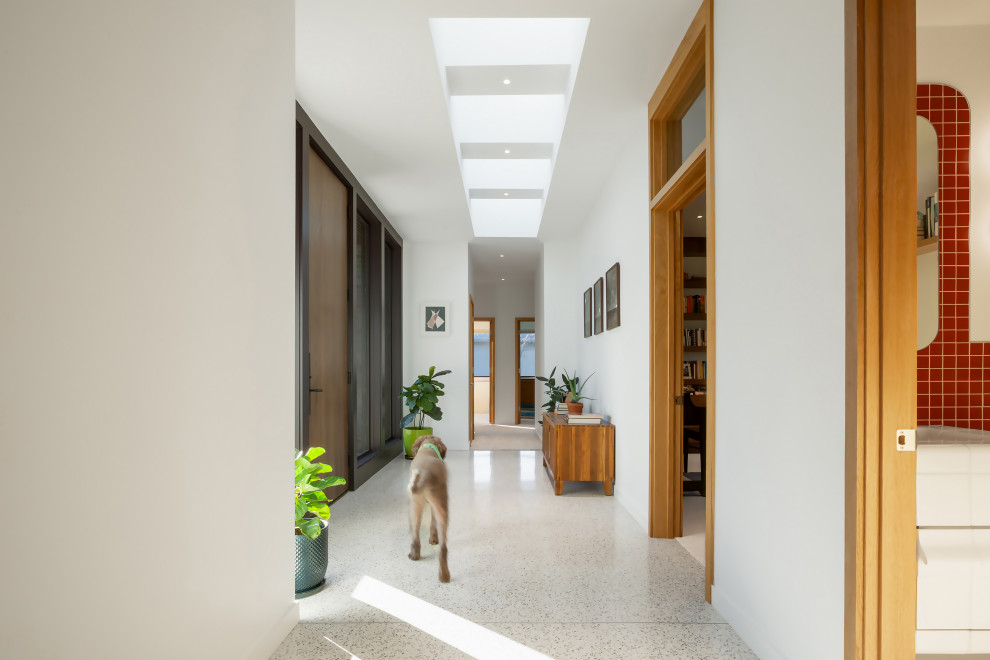 Cette image montre un couloir minimaliste avec un mur blanc, un sol en terrazzo et un sol multicolore.