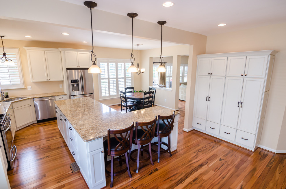 Photo of an expansive transitional l-shaped eat-in kitchen in DC Metro with with island, recessed-panel cabinets, white cabinets, granite benchtops, stainless steel appliances, an undermount sink and medium hardwood floors.