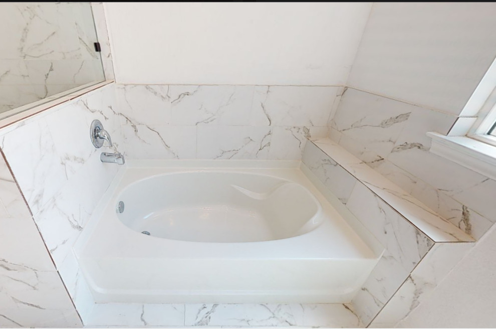This is an example of a mid-sized transitional master bathroom in Houston with shaker cabinets, white cabinets, a drop-in tub, a corner shower, a one-piece toilet, white tile, ceramic tile, white walls, porcelain floors, an undermount sink, quartzite benchtops, white floor, a hinged shower door, grey benchtops, an enclosed toilet, a double vanity, a built-in vanity, coffered and panelled walls.