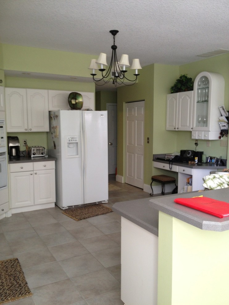Large transitional medium tone wood floor kitchen photo in Jacksonville with a farmhouse sink, shaker cabinets, white cabinets, quartzite countertops, white backsplash, ceramic backsplash, stainless steel appliances, green walls and an island