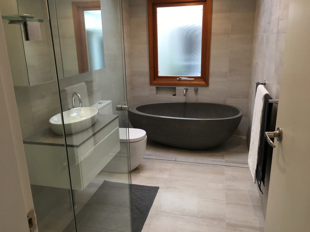 Photo of a contemporary master bathroom in Sydney with open cabinets, white cabinets, a freestanding tub, a corner shower, beige tile, ceramic tile, a vessel sink and quartzite benchtops.