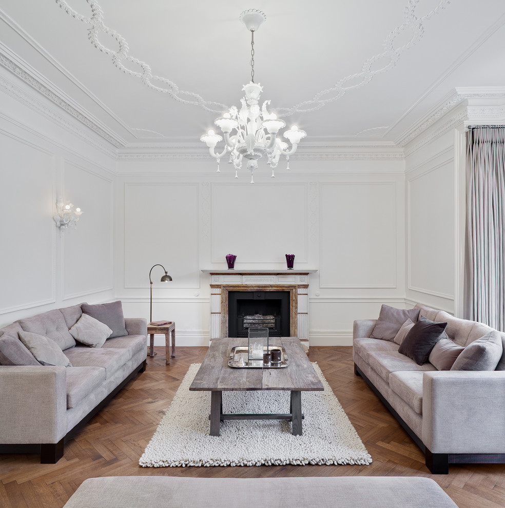 Photo of a transitional formal living room in London with a standard fireplace, white walls, light hardwood floors and a stone fireplace surround.