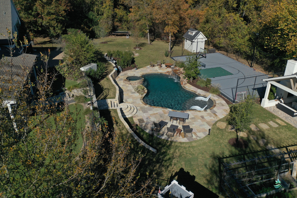 Immagine di un'ampia piscina naturale rustica personalizzata dietro casa con pavimentazioni in pietra naturale