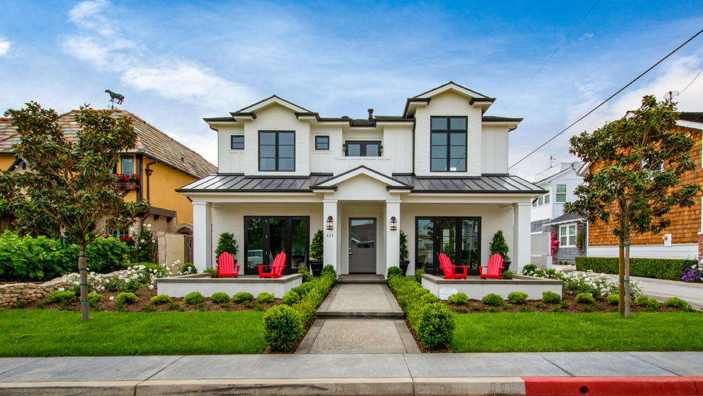 This is an example of a transitional two-storey white house exterior in Orange County with a hip roof and a metal roof.