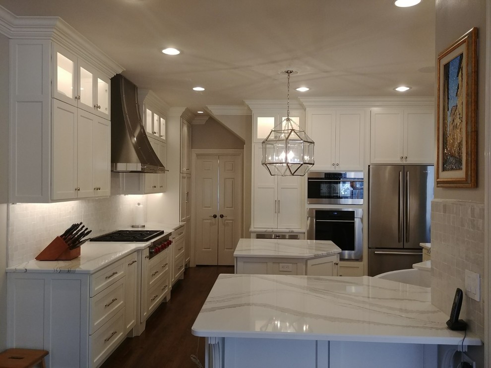 Inspiration for a large transitional single-wall dark wood floor and brown floor enclosed kitchen remodel in Nashville with a farmhouse sink, recessed-panel cabinets, white cabinets, quartzite countertops, white backsplash, subway tile backsplash, stainless steel appliances, an island and white countertops