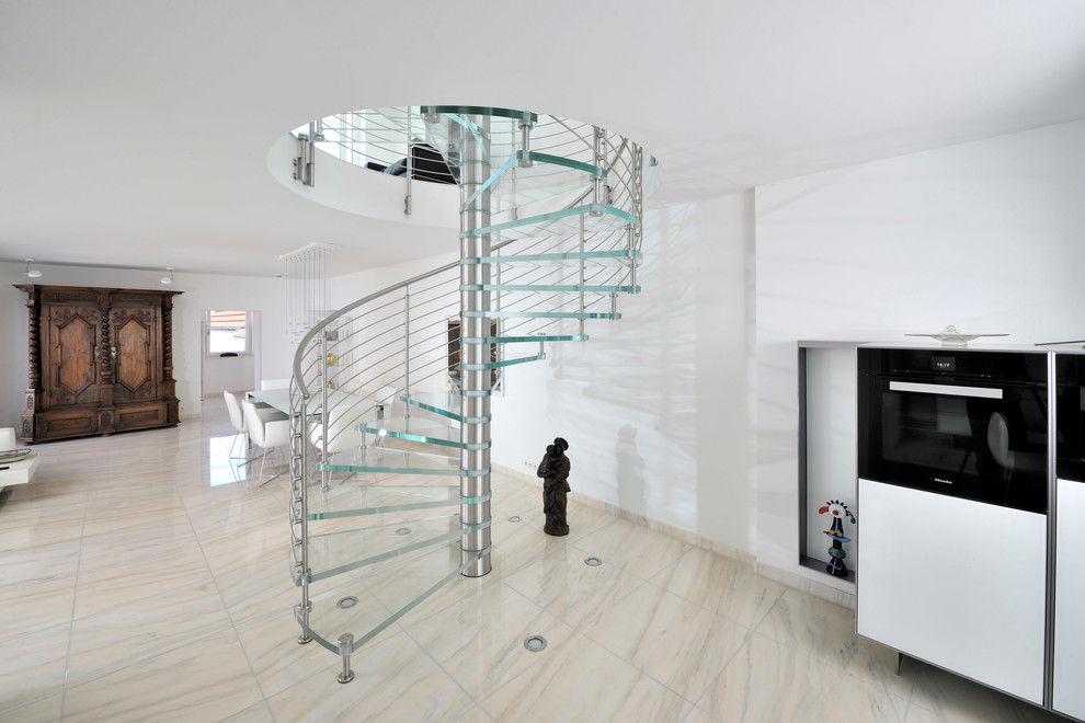 Photo of a large contemporary glass spiral staircase in Munich with open risers and metal railing.