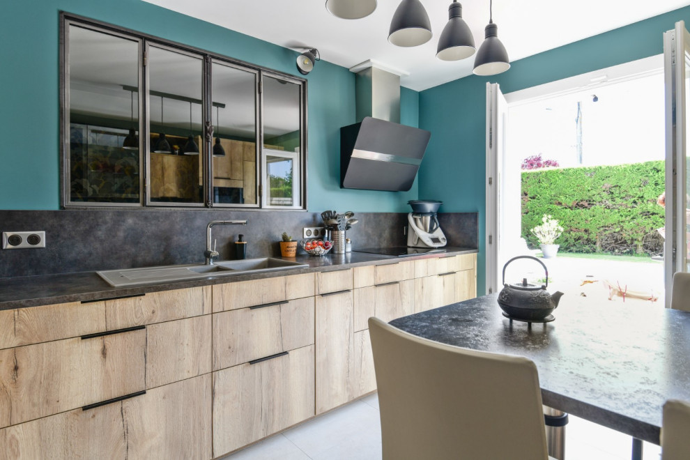 Mid-sized industrial l-shaped separate kitchen in Angers with a single-bowl sink, beaded inset cabinets, light wood cabinets, laminate benchtops, grey splashback, ceramic floors, with island, grey floor, grey benchtop and black appliances.