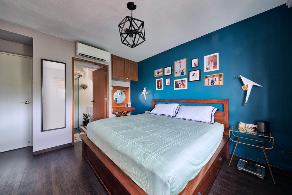This is an example of a transitional master bedroom in Singapore with blue walls and dark hardwood floors.