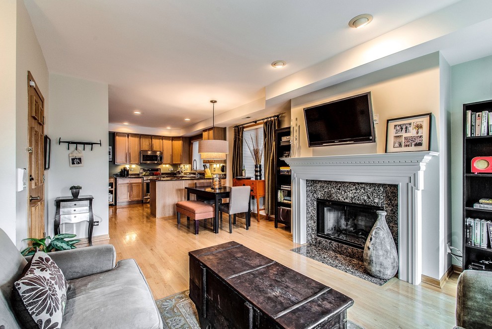 This is an example of a contemporary open concept living room in Chicago with a standard fireplace, a stone fireplace surround and a wall-mounted tv.