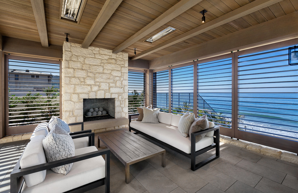 Inspiration for a beach style backyard patio in Orange County with tile, a roof extension and with fireplace.