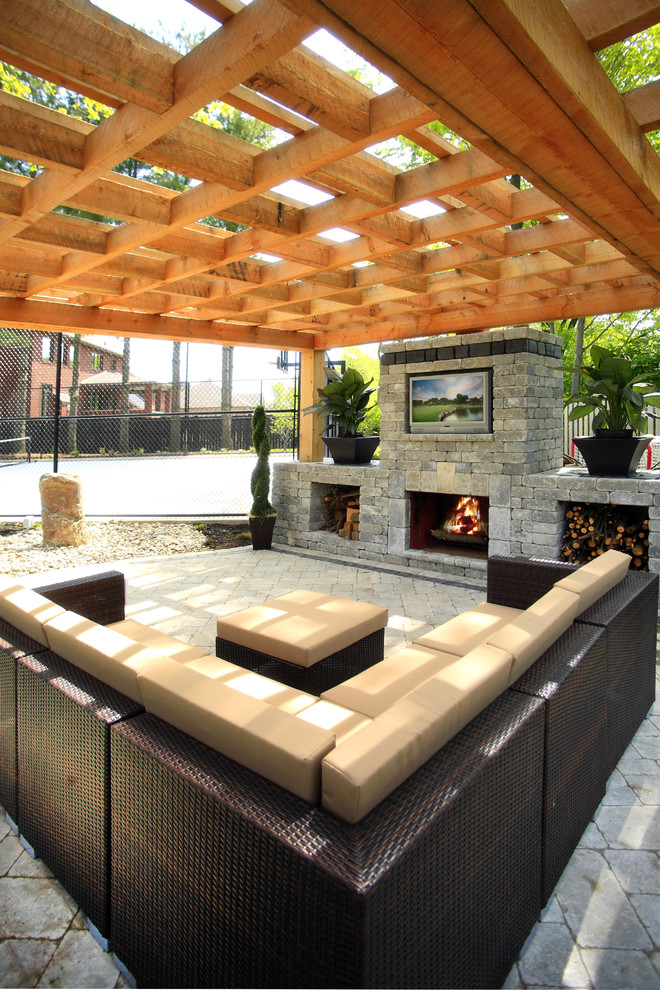 Design ideas for a mid-sized transitional backyard patio in Toronto with a fire feature, concrete pavers and a pergola.