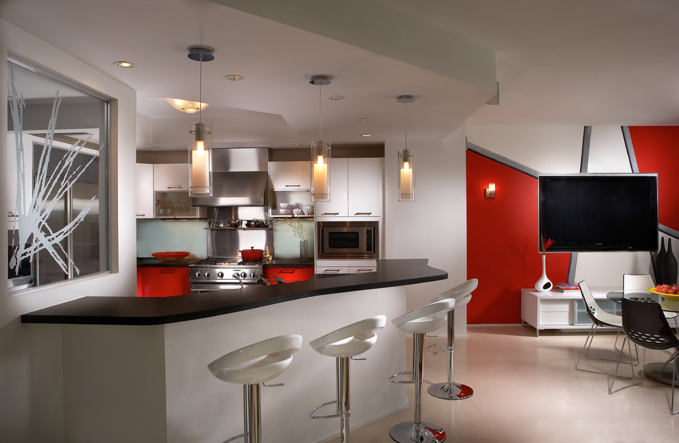 This is an example of a mid-sized contemporary l-shaped open plan kitchen in Miami with an undermount sink, flat-panel cabinets, red cabinets, granite benchtops, white splashback, glass sheet splashback, stainless steel appliances, marble floors and with island.