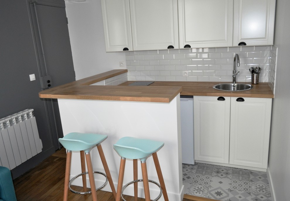 This is an example of a small scandinavian l-shaped eat-in kitchen in Paris with white splashback, matchstick tile splashback, ceramic floors and with island.