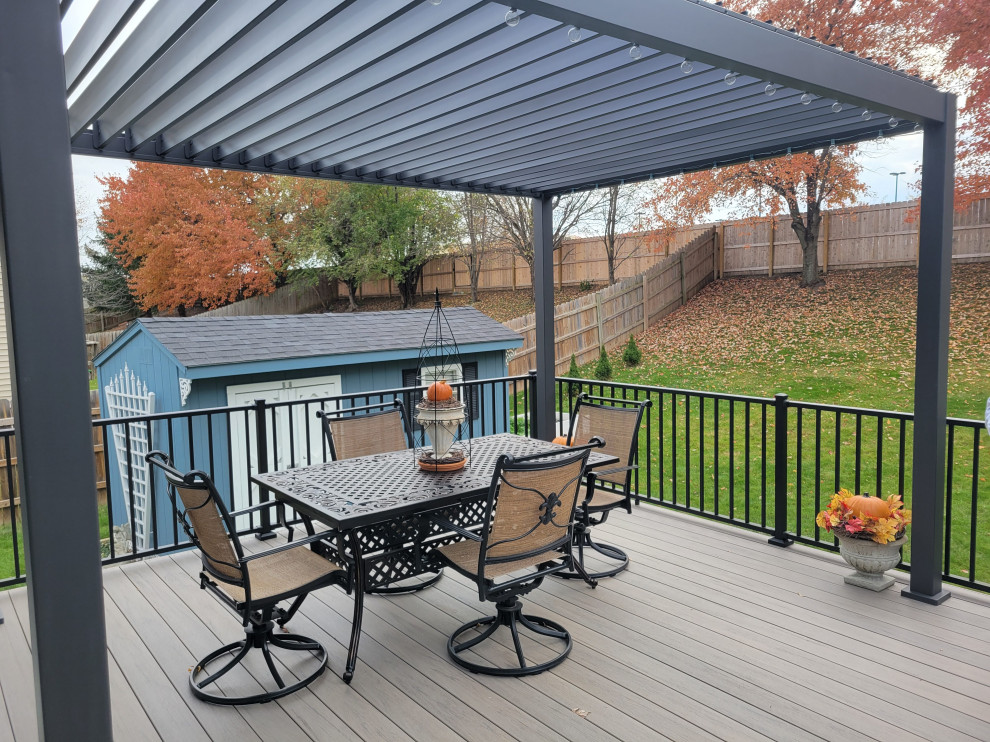 Example of a large backyard ground level metal railing deck design with a pergola