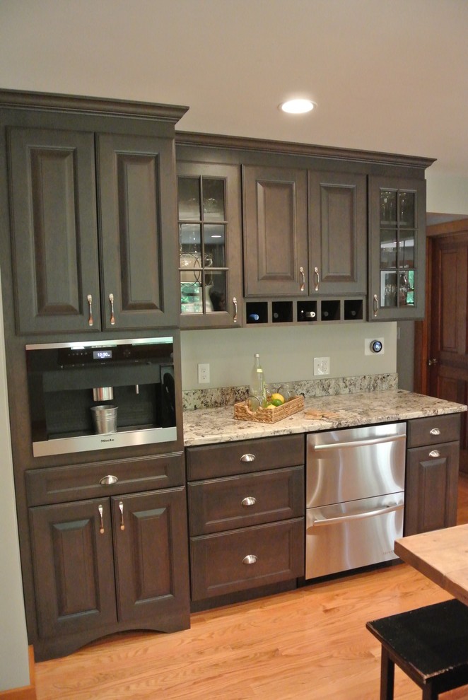 Example of a large transitional l-shaped light wood floor eat-in kitchen design in Boston with a farmhouse sink, shaker cabinets, gray cabinets, granite countertops, white backsplash, ceramic backsplash, stainless steel appliances, an island and gray countertops