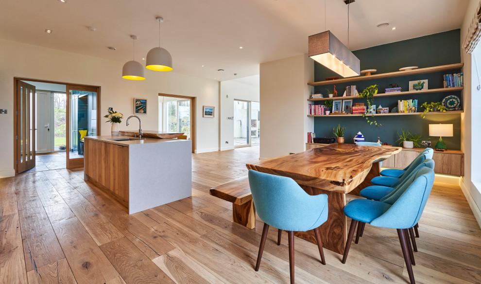 Photo of a large contemporary single-wall open plan kitchen in Other with a drop-in sink, shaker cabinets, blue cabinets, quartzite benchtops, grey splashback, stone tile splashback, white appliances, medium hardwood floors, with island, brown floor and grey benchtop.