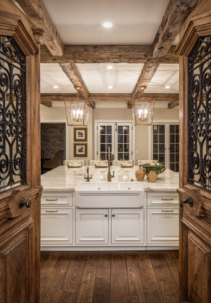 Design ideas for a large traditional l-shaped kitchen in Omaha with a farmhouse sink, raised-panel cabinets, white cabinets, granite benchtops, white splashback, brick splashback, stainless steel appliances, medium hardwood floors, with island, brown floor and beige benchtop.