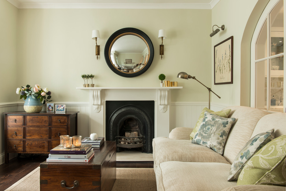 Small traditional living room in London with green walls, dark hardwood floors and a standard fireplace.