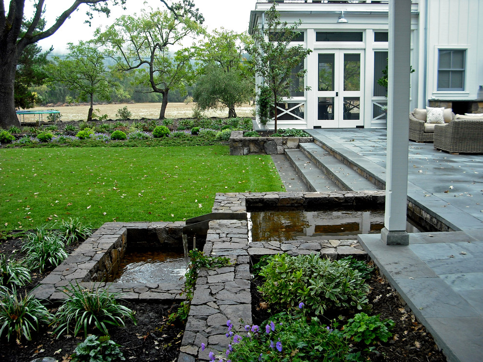Design ideas for a large country backyard garden in San Francisco with a water feature and natural stone pavers.