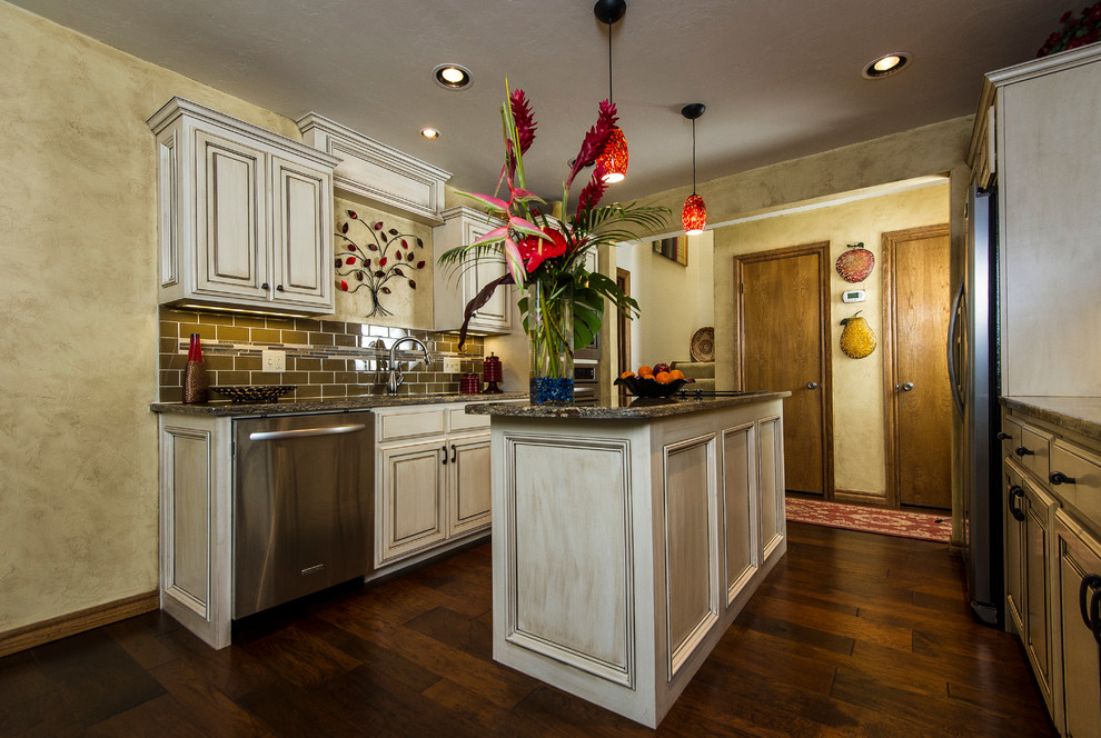 Mid-sized transitional galley dark wood floor enclosed kitchen photo in Oklahoma City with distressed cabinets, brown backsplash, stainless steel appliances, an island, raised-panel cabinets, granite countertops, subway tile backsplash and an undermount sink