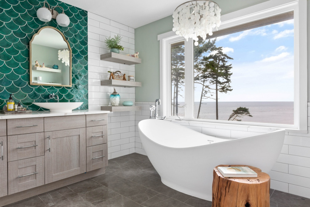Photo of a beach style bathroom in Seattle with shaker cabinets, grey cabinets, a freestanding tub, white tile, grey walls, a vessel sink, grey floor and white benchtops.