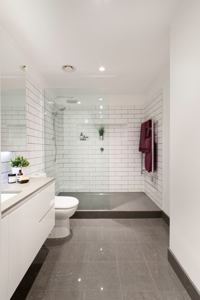 Inspiration for a mid-sized modern master bathroom in Melbourne with an undermount sink, flat-panel cabinets, white cabinets, engineered quartz benchtops, an open shower, white tile, porcelain tile, white walls and porcelain floors.