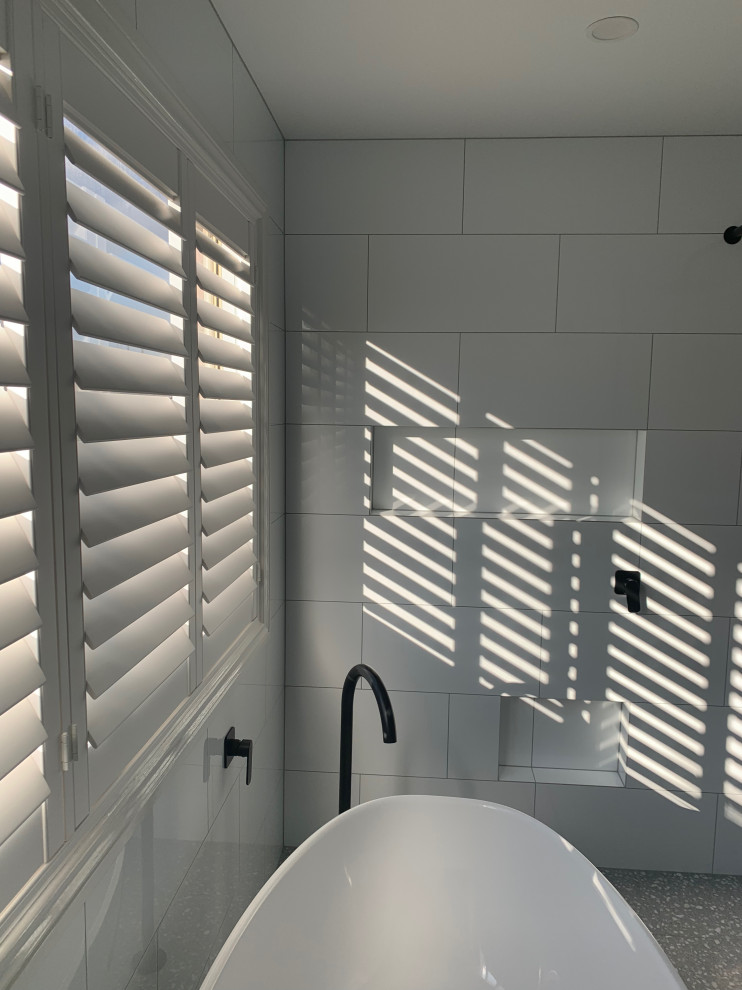 This is an example of a large modern wet room bathroom in Melbourne with shaker cabinets, white cabinets, a freestanding tub, a one-piece toilet, white tile, porcelain tile, white walls, terrazzo floors, a vessel sink, granite benchtops, grey floor, an open shower, a double vanity, a freestanding vanity and grey benchtops.