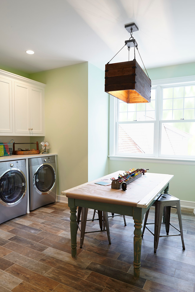 Photo of a large beach style single-wall utility room in Minneapolis with recessed-panel cabinets, white cabinets, green walls and a side-by-side washer and dryer.