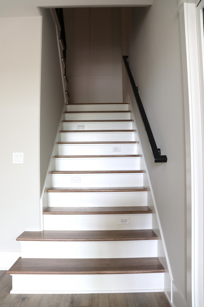 На фото: п-образная деревянная лестница с деревянными ступенями, металлическими перилами и панелями на стенах с