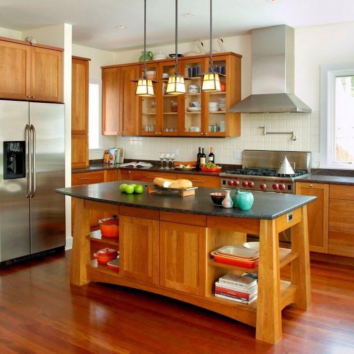 Design ideas for a mid-sized arts and crafts u-shaped eat-in kitchen in New York with with island, shaker cabinets, medium wood cabinets, granite benchtops, beige splashback, terra-cotta splashback, stainless steel appliances, an undermount sink, medium hardwood floors, brown floor and black benchtop.