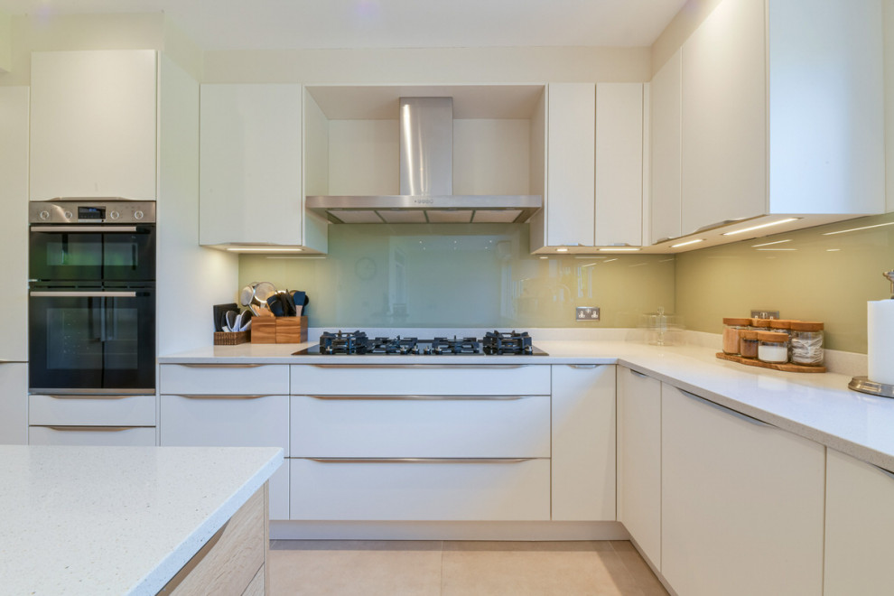Inspiration for a large modern l-shaped open plan kitchen in London with a double-bowl sink, shaker cabinets, white cabinets, limestone benchtops, grey splashback, slate splashback, stainless steel appliances, with island and white benchtop.