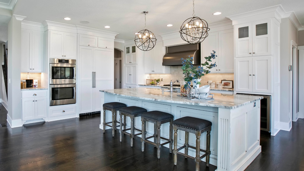 Design ideas for a transitional l-shaped kitchen in Minneapolis with white cabinets, granite benchtops, beige splashback, stainless steel appliances, dark hardwood floors, with island and shaker cabinets.