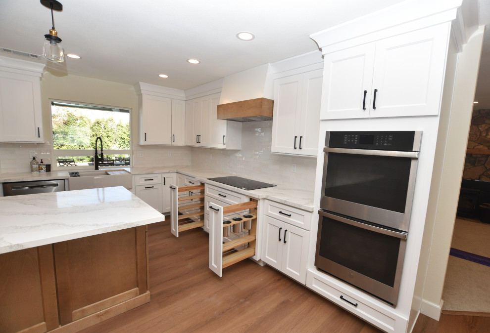 Inspiration for a large transitional l-shaped vinyl floor and brown floor open concept kitchen remodel with a farmhouse sink, shaker cabinets, white cabinets, quartz countertops, white backsplash, ceramic backsplash, stainless steel appliances, an island and multicolored countertops