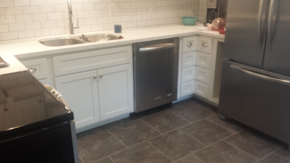 Example of an u-shaped eat-in kitchen design with an undermount sink, shaker cabinets, white cabinets, white backsplash, subway tile backsplash and stainless steel appliances