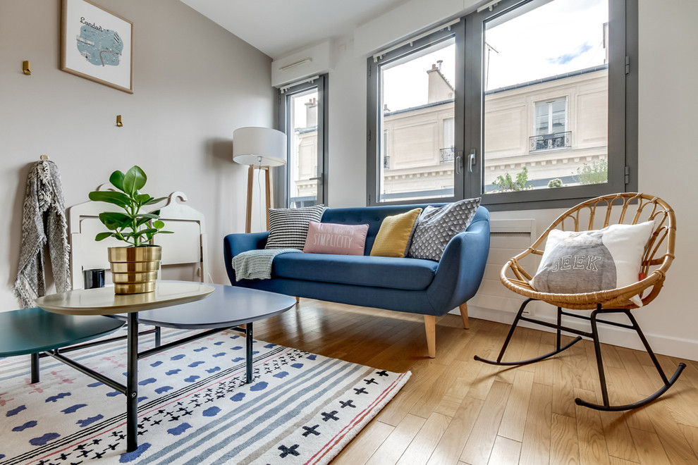 Photo of a small scandinavian open concept living room in Paris with beige walls and light hardwood floors.