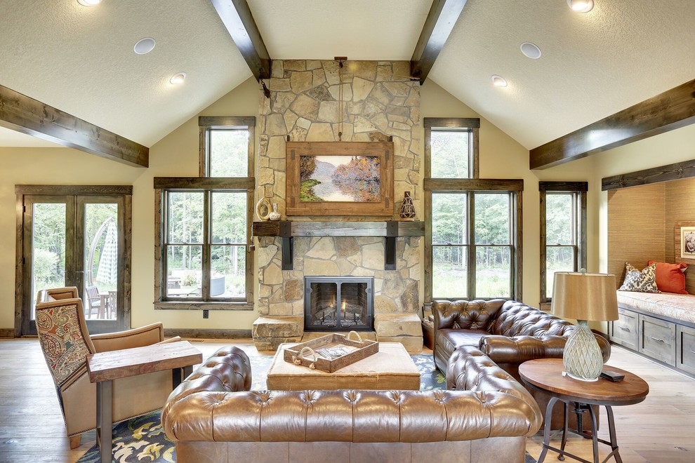 Photo of a country living room in Minneapolis with beige walls, a standard fireplace, a stone fireplace surround and light hardwood floors.