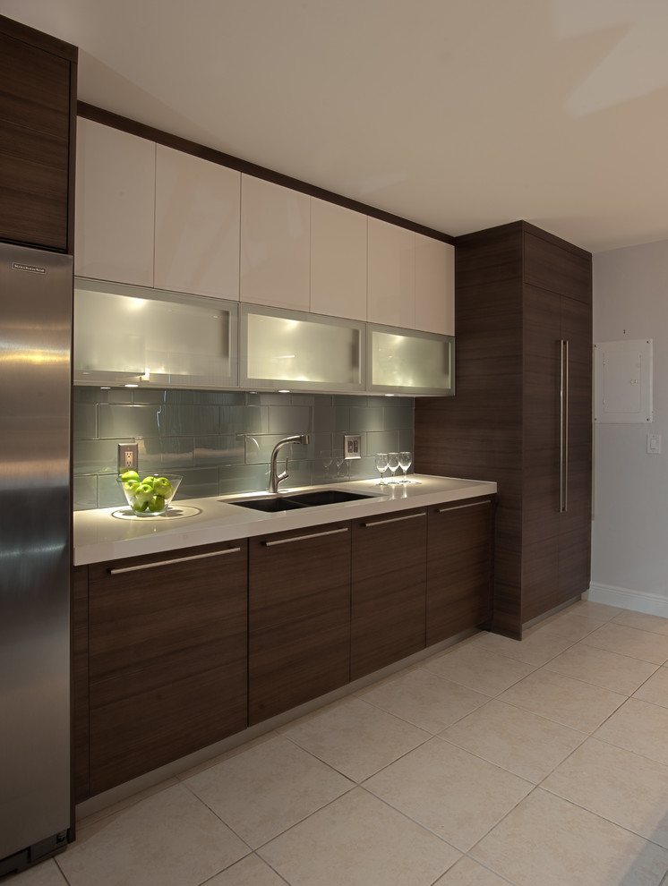 Mid-sized modern kitchen in Miami with a drop-in sink, flat-panel cabinets, medium wood cabinets, solid surface benchtops, green splashback, mosaic tile splashback, stainless steel appliances, ceramic floors and no island.